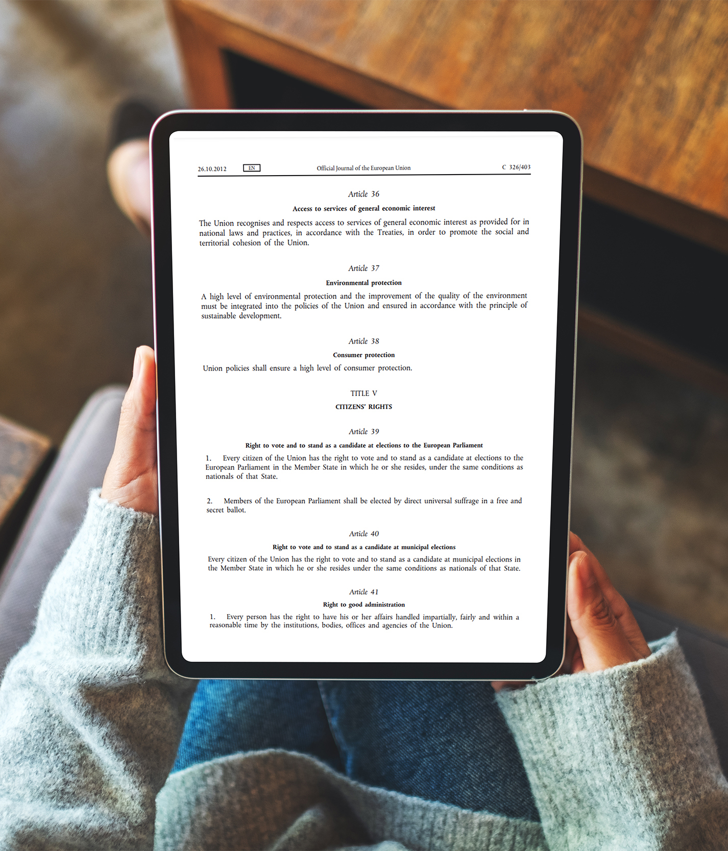 A person holds a tablet displaying the text of the EU Charter of Fundamental Rights, specifically articles related to environmental protection, consumer protection, and citizens' rights.